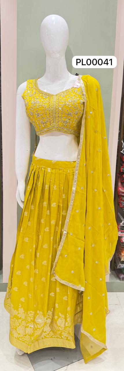 A bright yellow traditional Indian outfit displayed on a white mannequin, featuring a sleeveless embroidered blouse, a matching flared skirt, and a draped dupatta. A product code label 'PL00041' is visible near the top right.